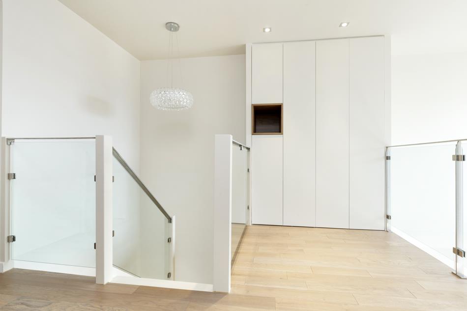 Arrivée d'escalier lumineuse, placard aux portes coplanaires et niche réhaussée par le bois teinté huilé 