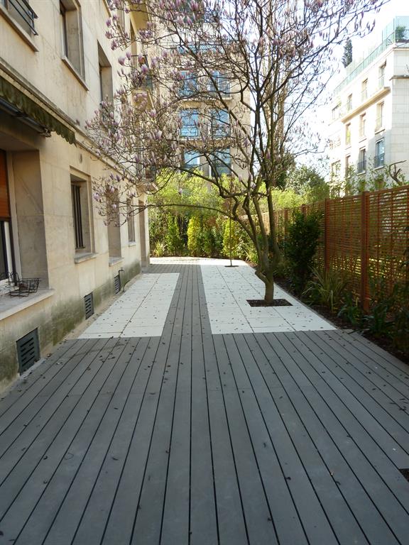 Terrasse en bois composite gris encastrées dans un dallage clair