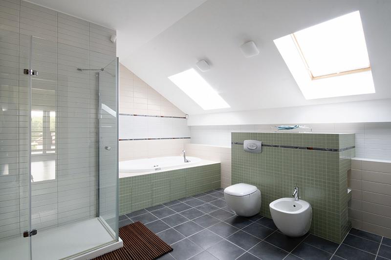 Salle de bain moderne sous les toits avec douche, baignoire, WC et bidet.  