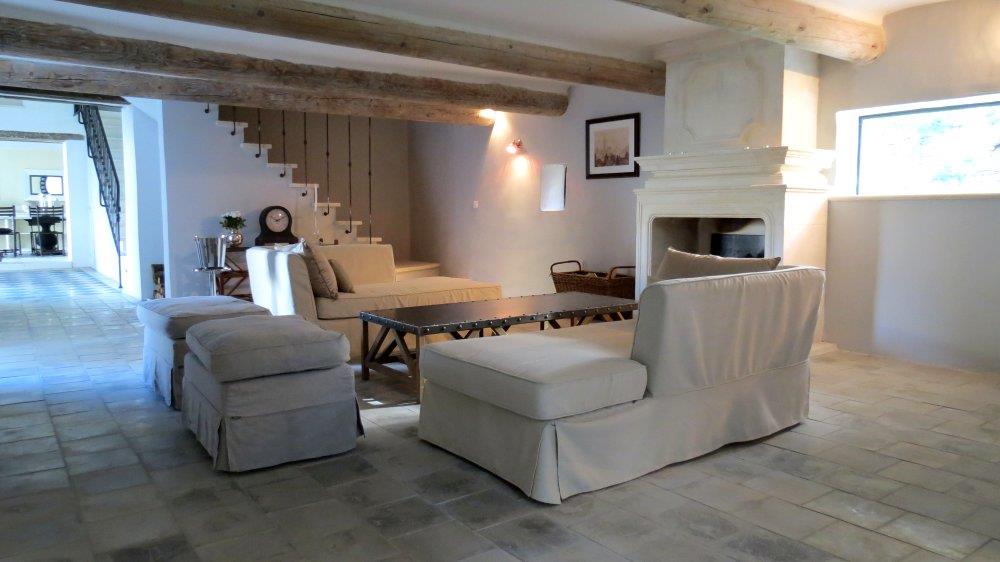 Salon avec cheminée ancienne et poutres apparentes en bois naturel