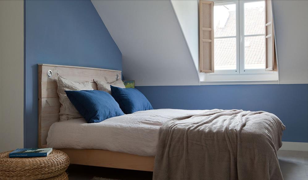 Chambre bleue mansardée de style scandinave avec lit en bois