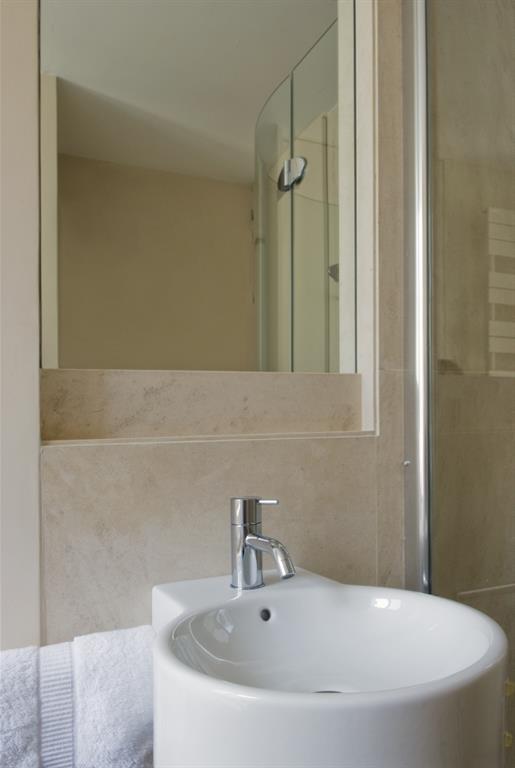 Salle de bain avec lavabo blanc et marbre sur le mur