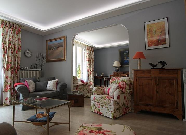 Salon avec fauteuils en tissus à motifs floral et meubles anciens