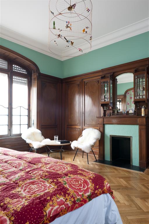 Chambre adultes classique avec cheminée et coin salon. Bois foncé verni 