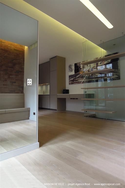 Entrée avec mirroir donnant sur espace ouvert avec cuisine taupe