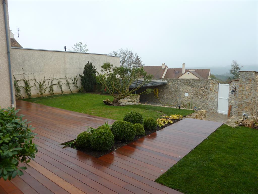 La terrasse en bois se prolonge jusqu'au portail pour créer un chemin d'accès