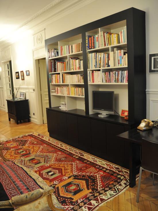 Bibliothèque contemporaine noire dans un appartement à moulures