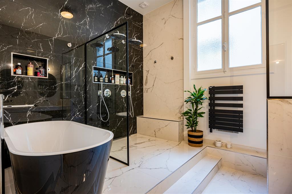 Aménagement d'une grande salle de bain en marbre noir et blanc comportant