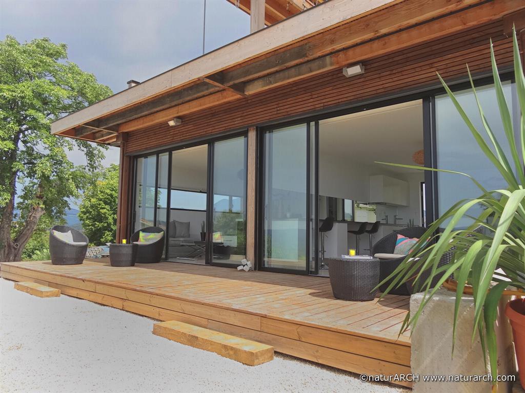 Extension avec de larges portes-fenêtres ouvrant sur une terrasse en bois