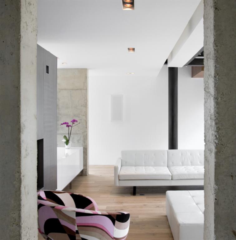 Salon avec canapé en cuir blanc et mur en béton brut