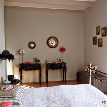 Chambre chic dans une maison charentaise.
Murs et poutres repeints en gris clair, mobilier noir et quelques touches de rose.  Domozoom