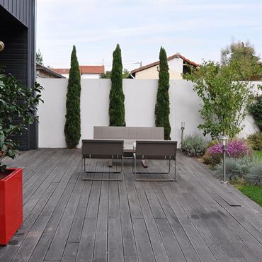 Terrasse en bois dans un jardin de ville avec équipements design