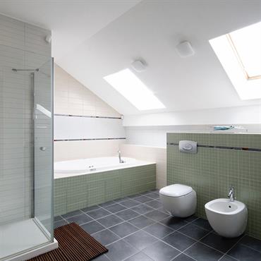 Salle de bain moderne sous les toits avec douche, baignoire, WC et bidet.  