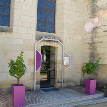 Entrée de café, façade en pierres, jardinières violettes 
