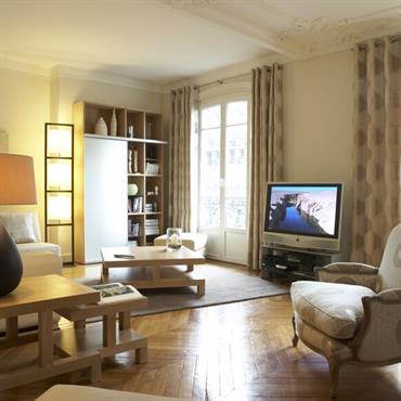 Salon classique d'un appartement avec moulures au plafond, et parquet à chevrons 