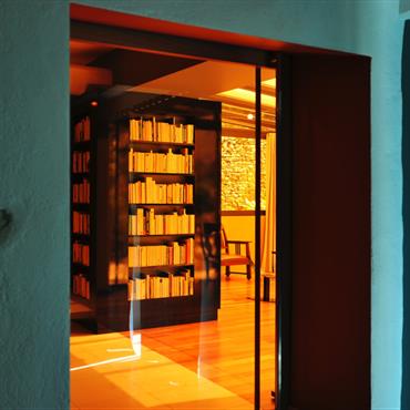 Une porte coulissante en verre orange s’escamote dans la double cloison derrière la bibliothèque et sépare la cuisine du séjour - véranda.
 