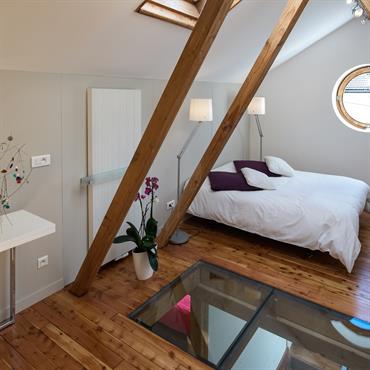 La chambre est accessible par un escalier. Le meuble sert de rangement et de garde corps. La charpente sépare la partie chambre de la partie sale de bain et encadre ...