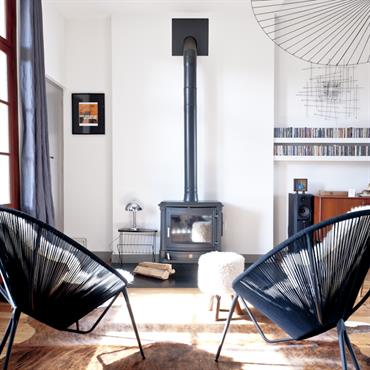 Coin cheminée cosy. Tapis en peau, parquet, murs blancs 