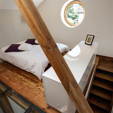 La chambre est accessible par un escalier. Le meuble sert de rangement et de garde corps. La charpente sépare la partie chambre de la partie salle de bain et encadre ...