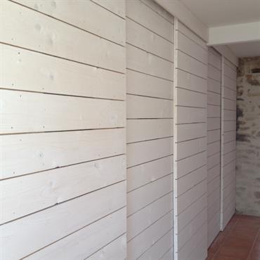 Dressing aux portes coulissantes en lattes de bois blanc 