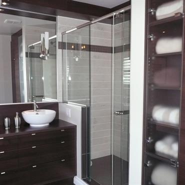 Salle de bain avec meuble double vasque en bois, placard verre et bois, douche. 