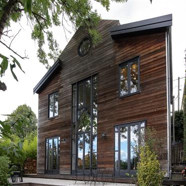 Pour atténuer son coté massif, la maison est comme posée sur une terrasse suspendue. Les graviers blancs illuminent le bardage en redcedar de la maison. les marches d'escalier en graviers ...