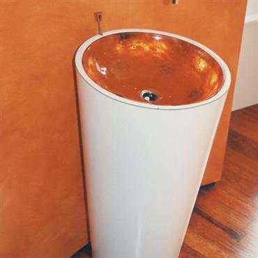 Vasque à poser ronde. Extérieur blanc, intérieur cuivré qui reprend les teintes du mur enduit et du parquet huilé. 