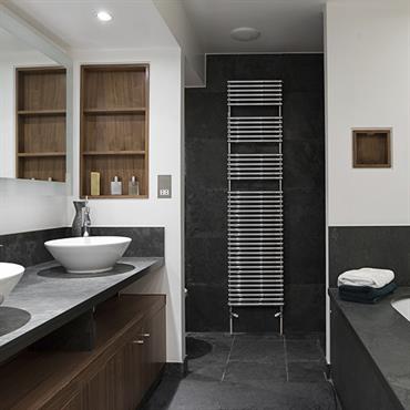Sobre et contemporaine, cette salle de bain associe le côté minéral de la pierre grise et le bois du meuble sous vasque et de l'habillage des niches murales. 