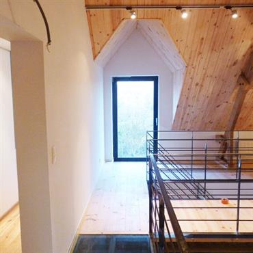 Sous pente avec lambris en pin aménagée d'une mezzanine dont une partie est en verre avec garde corps en métal. 