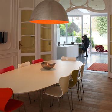 Salle à manger moderne. Les chaises aux couleurs différentes et la suspension intérieur orange dynamisent l'espace. 