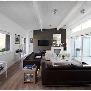 Salon blanc, mobilier et mur du fond noir. Lumière naturelle traversante 