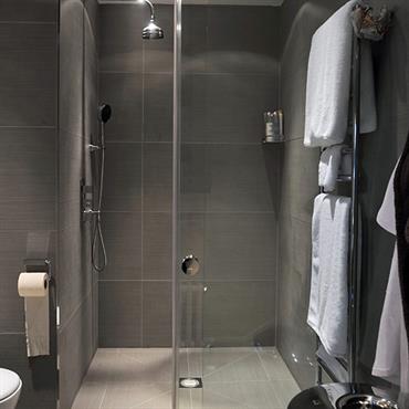 Dans cette douche à l'italienne, un carrelage gris a été choisi pour un rendu contemporain. Les deux nuances de gris donnent un caractère très déco à la salle de bain. 