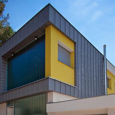 Villa avec façade en zinc, et mur béton jaune  