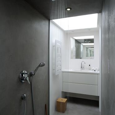 La salle de bain, mi blanche mi béton, offre la simplicité d'un environnement zen. 