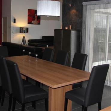 Salle à manger avec carrelage sombre, chaises noires et table en bois de couleur naturelle 