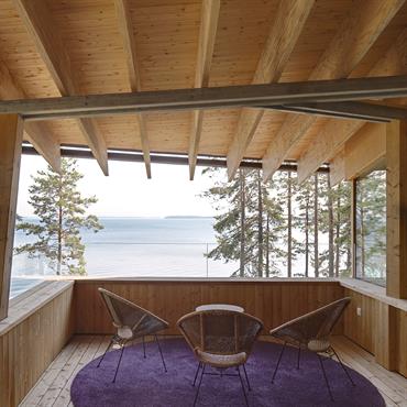 Terrasse nichée sous l'auvent, le garde coprs en verre permt une large vue sur le lac Saimaa 