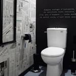 Toilettes avec un mur papier journal et un mur noir de type ardoise