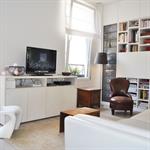 Salon blanc avec rangements bibliothèque et coin télé