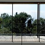 Vue sur la mer et la vagétation à travers les grandes baies vitrées de l'étage