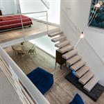 L’escalier suspendu en chêne blanchi qui monte à la mezzanine du loft est sans limon