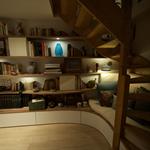 Aménagement sous l'escalier constitué d'un coin lecture avec banquette et étagères bibliothèque