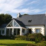 Véranda avec une toiture en ardoise et des baies vitrées